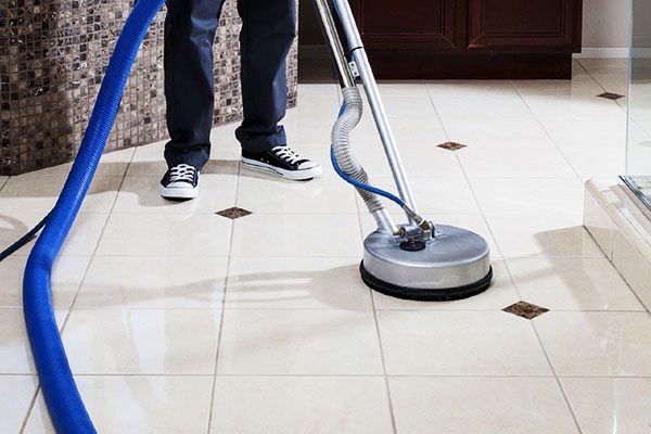 Person cleaning the kitchen tile with a buffer machine
